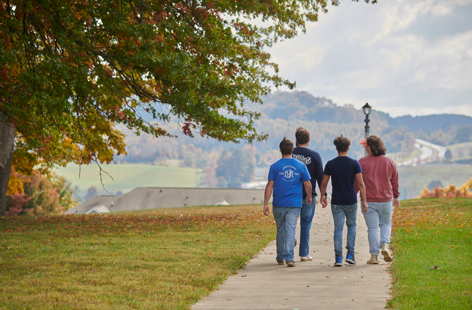 四个学生走在LMU校园的人行道上.