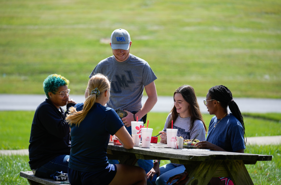一群学生在野餐桌旁吃午饭. 